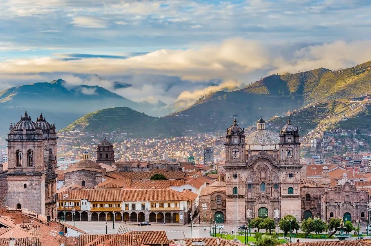 The churches of the main square in Cusco with green mountains behind