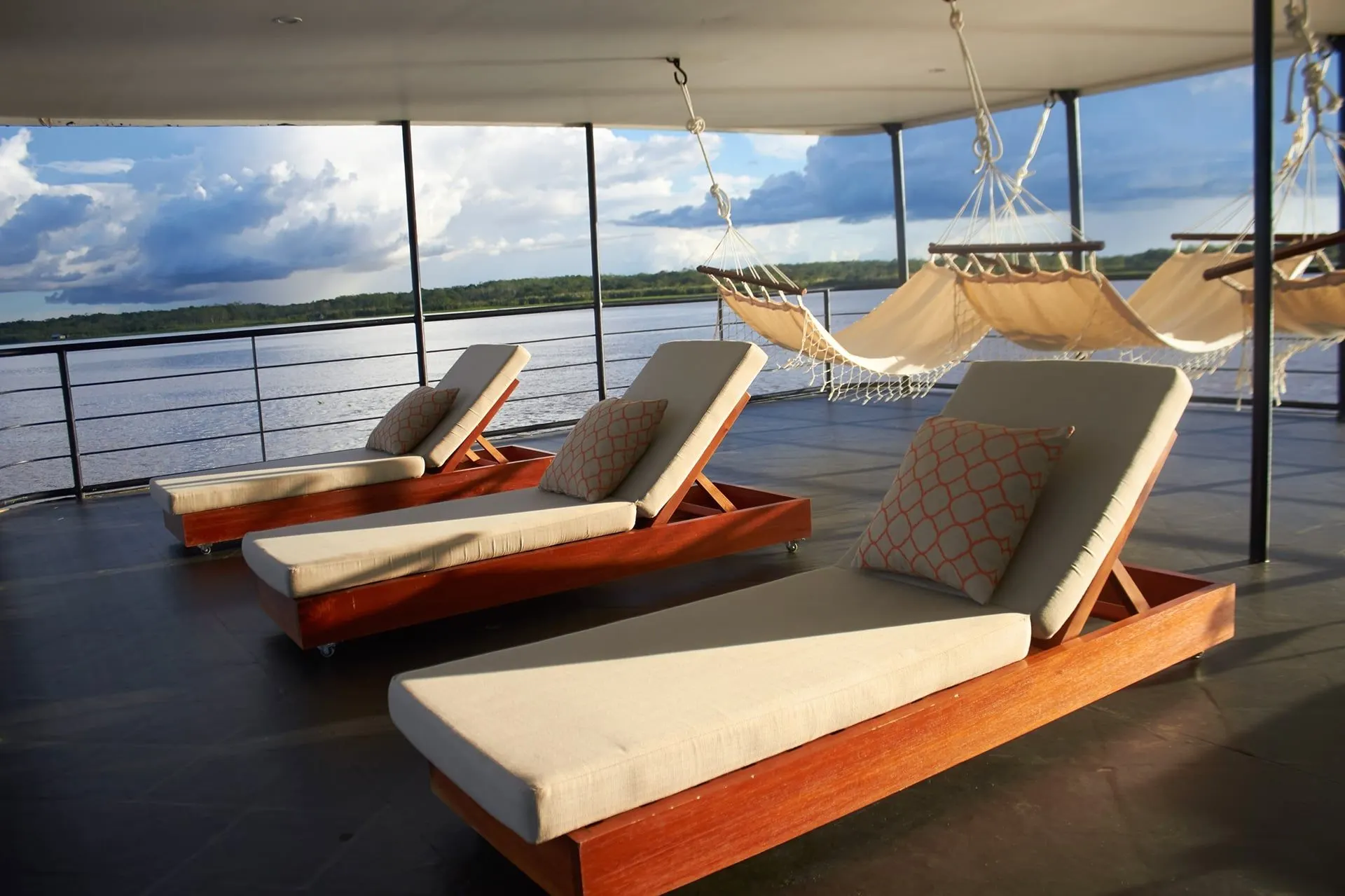 Sun loungers and hammocks on a shaded upper deck looking over the river