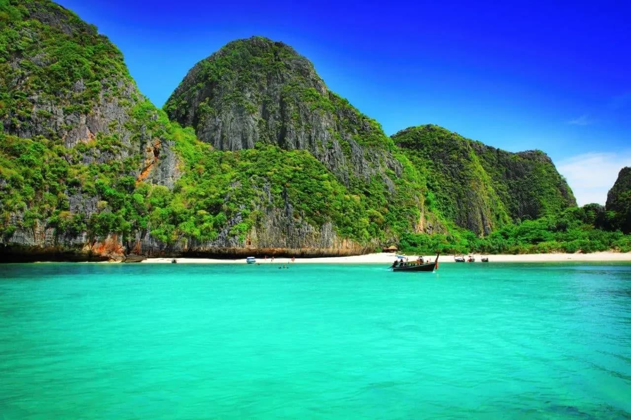 Green limestone peaks above an emerald bay and a white sand beach