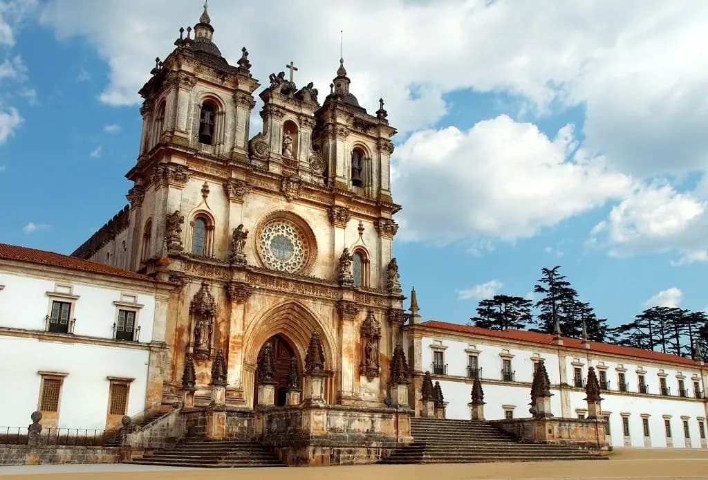 The baroque facade of the Alcobaça Monastery under a summer sky