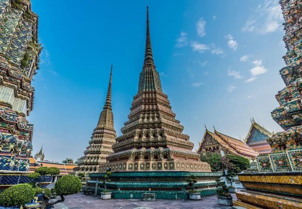 Tall tiled chedis in the grounds of Wat Pho under a blue sky