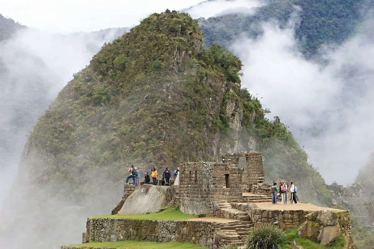 Visitors on a stone terrace at Machu Picchu with cloud on the peaks