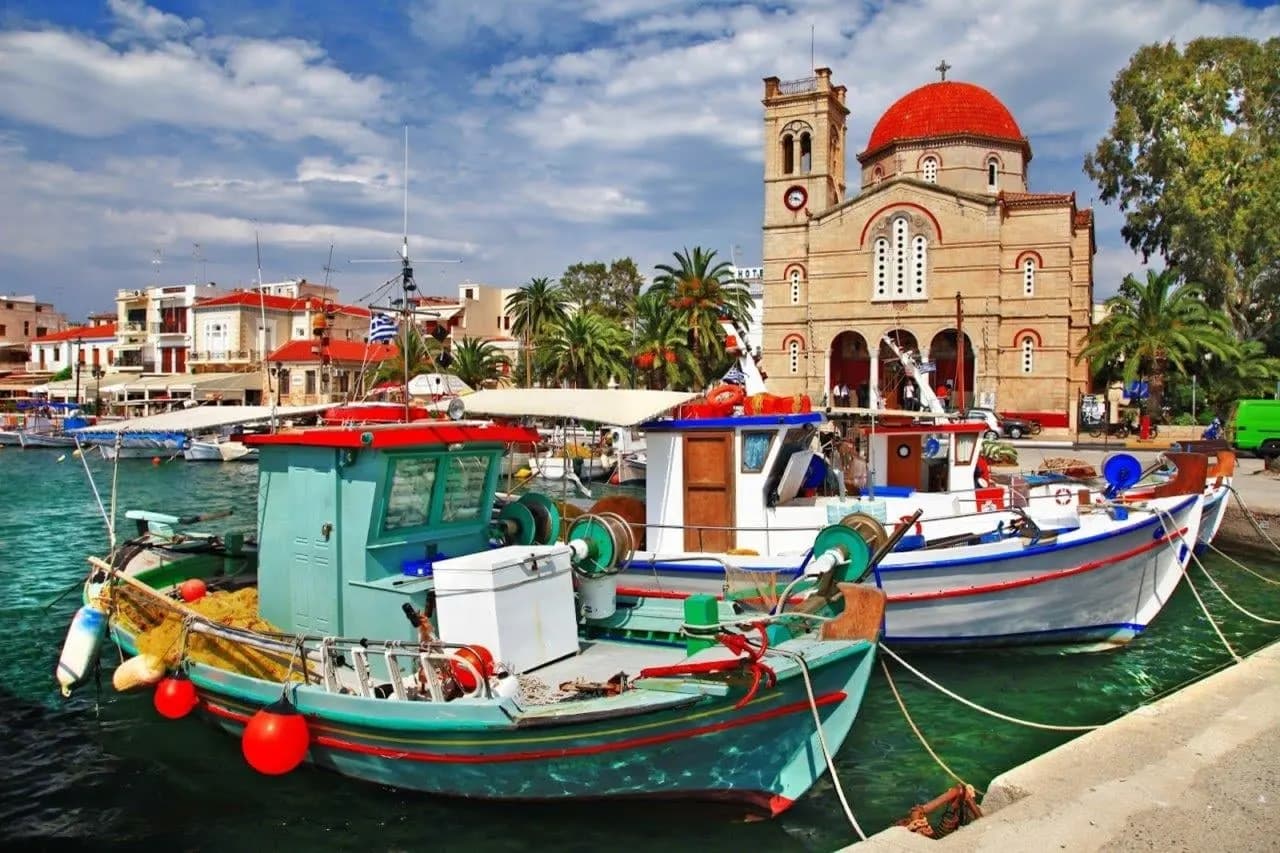 Painted fishing boats in an island harbour, below a church with a red dome