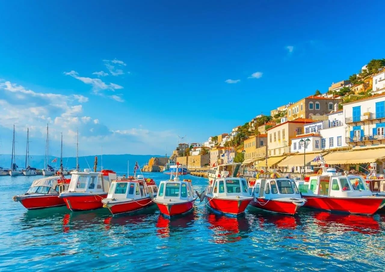 Red and white water taxis moored in front of a hillside island town