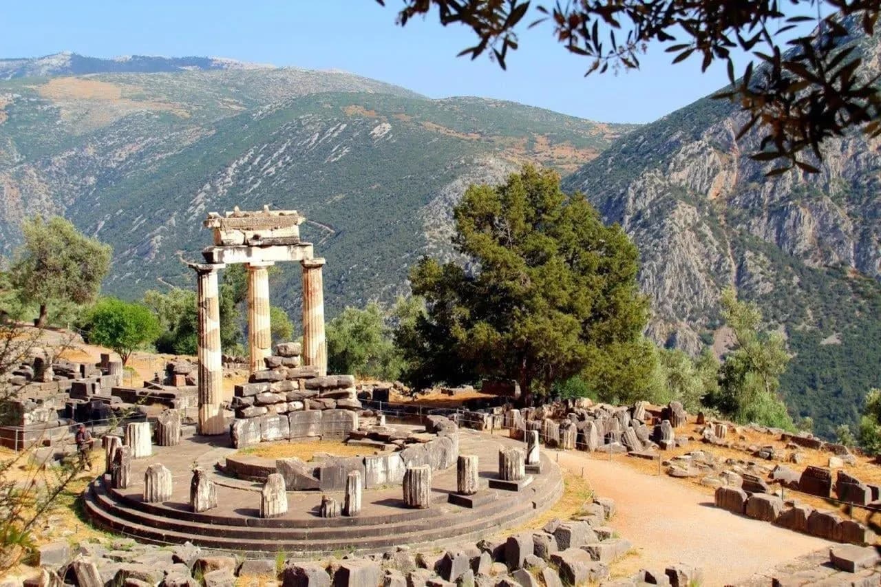 The round Tholos at Delphi among pines, below steep mountain slopes
