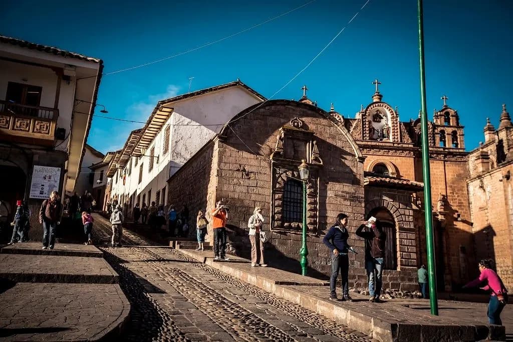 A cobbled street leading to a colonial stone church in Cusco