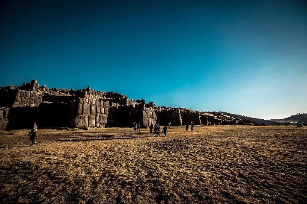 The walls of Sacsayhuaman across a wide esplanade under a deep blue sky
