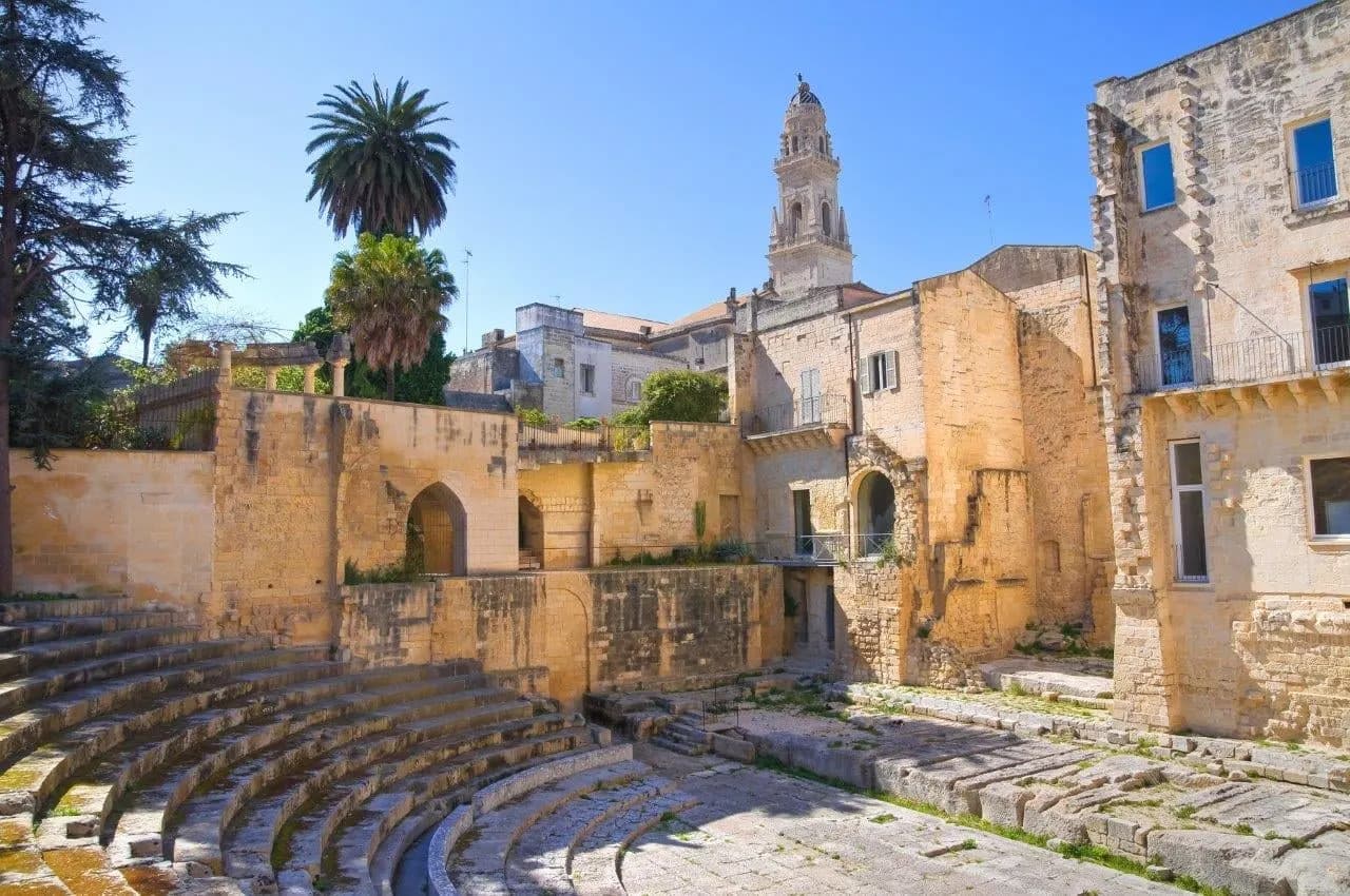 Curved seating of an old Roman theatre beneath a cathedral bell tower in Lecce