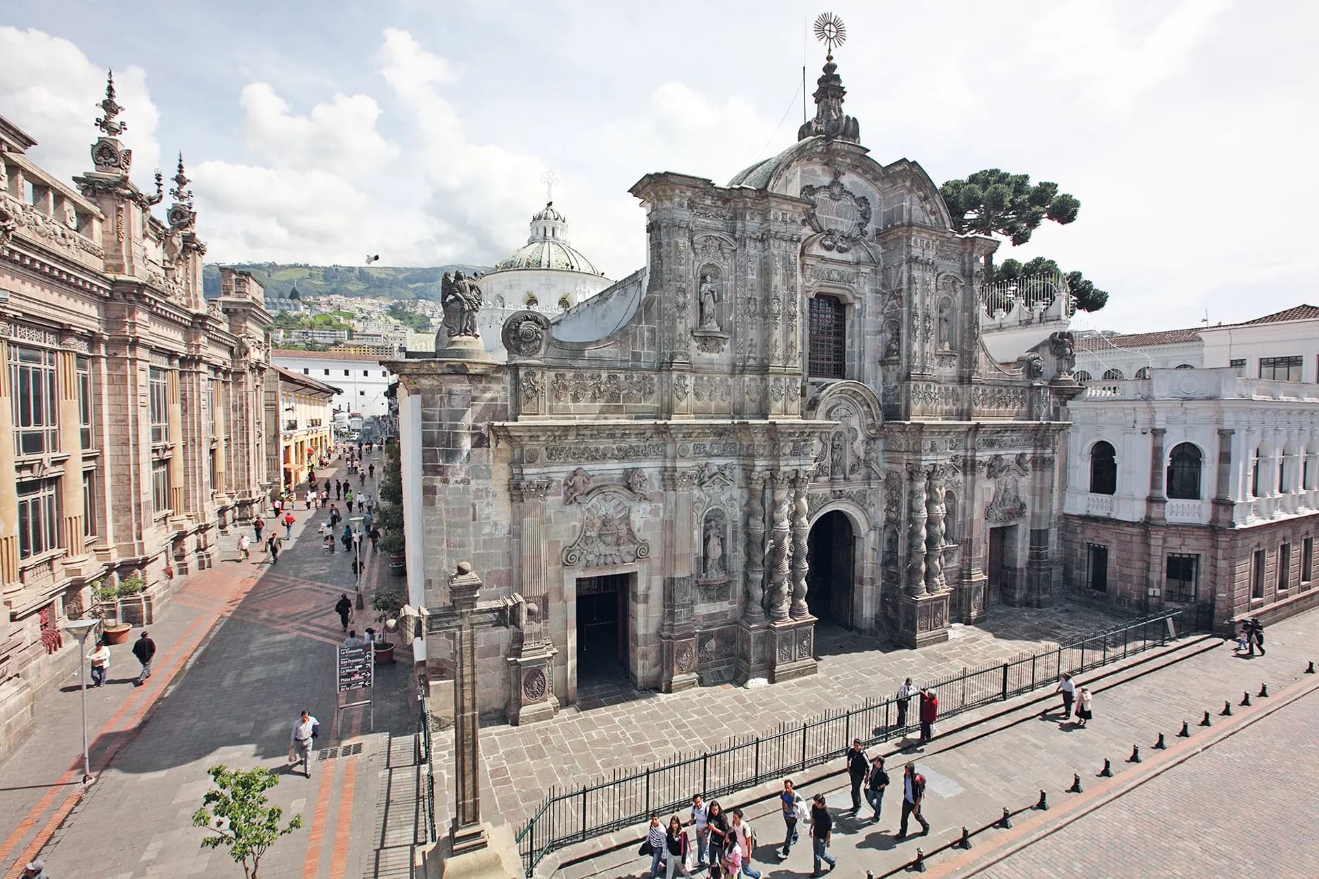 The carved stone facade of a baroque church on a sloping street