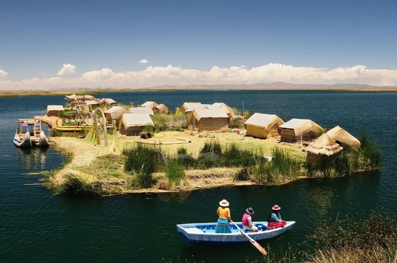 A floating reed island with thatched huts and a rowing boat on Lake Titicaca
