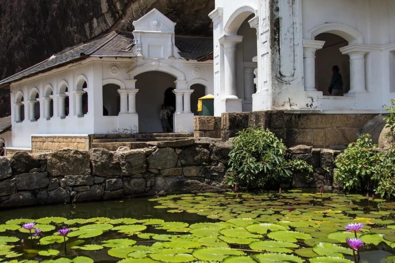 A white temple facade above a pond of water lilies