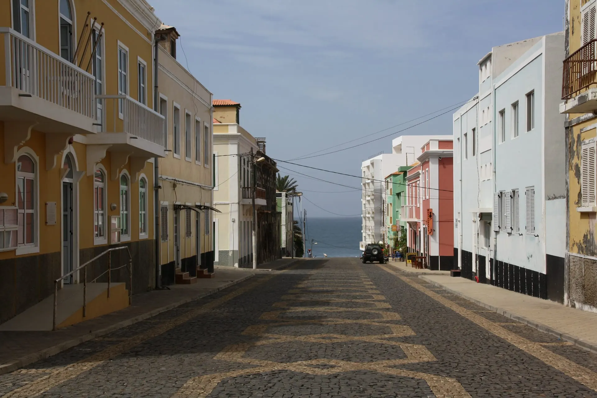 A cobbled street of painted houses running down to the sea
