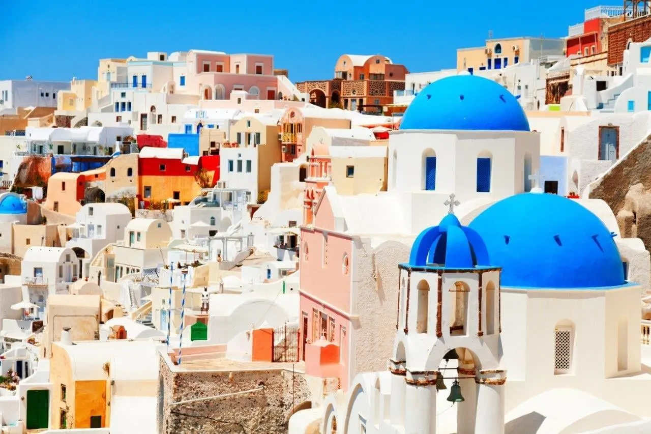 Blue domes in front of white and colourful houses on Santorini