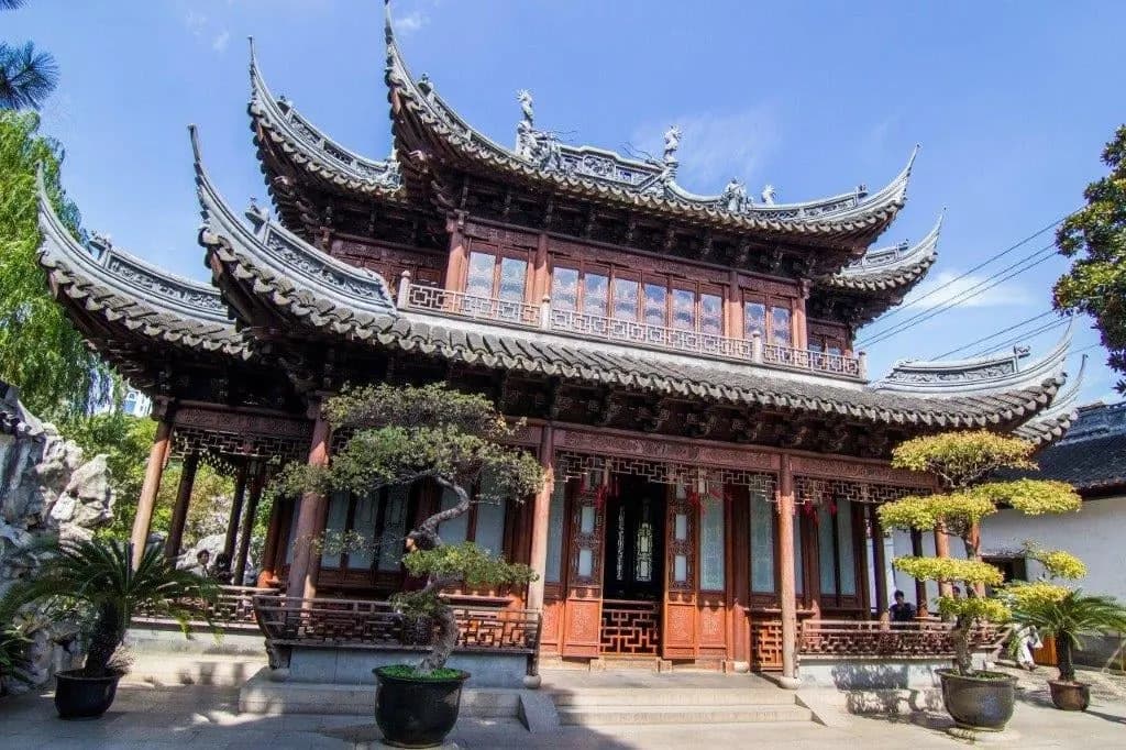 A two-storey pavilion with upswept eaves and bonsai pines in Yu Garden