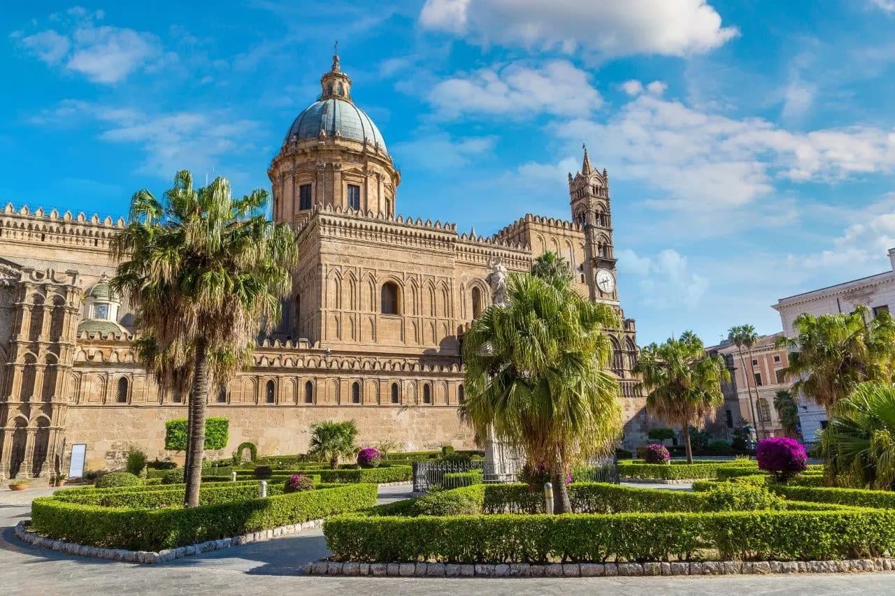 Palermo Cathedral with its dome and bell tower above a garden of palms