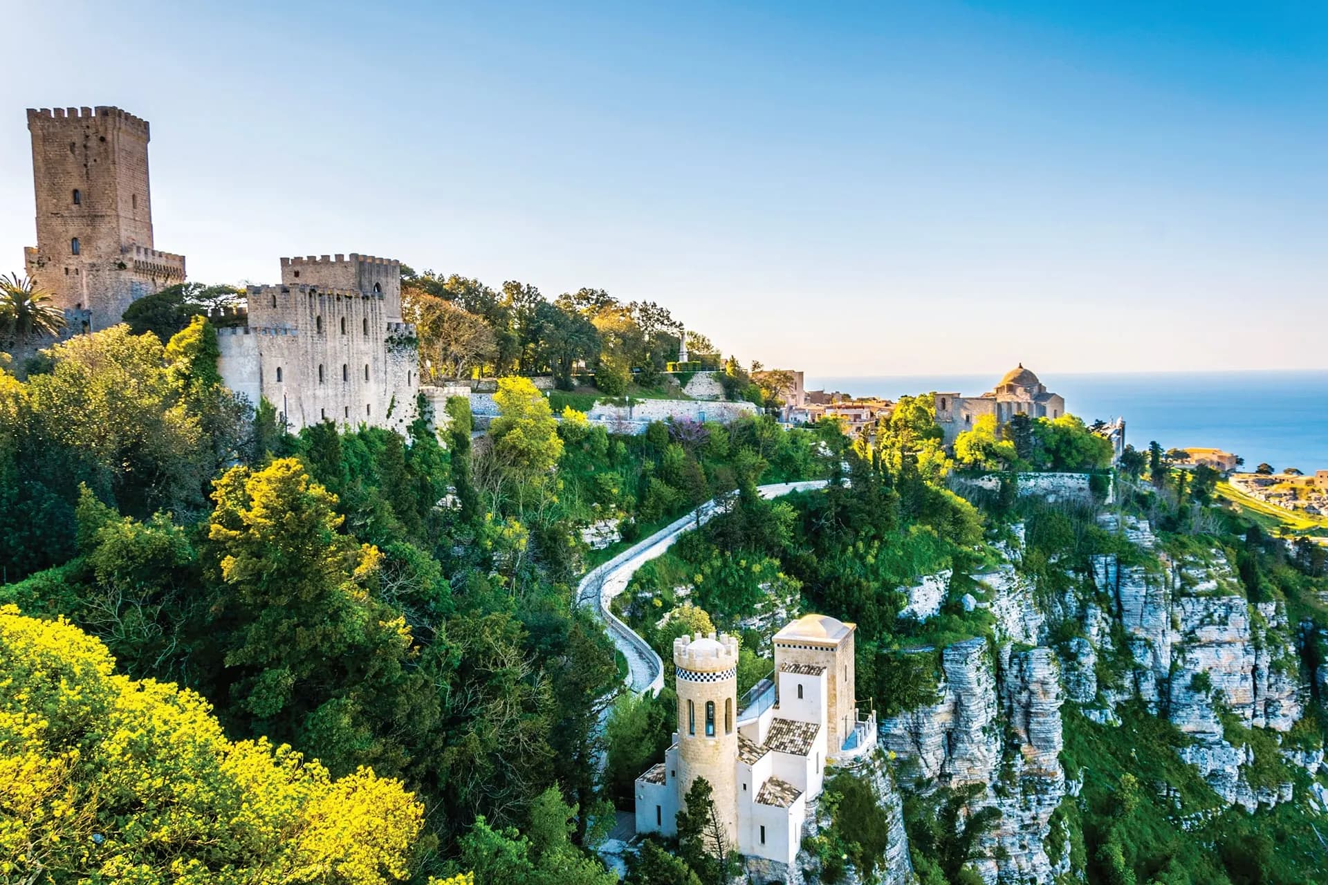 The medieval towers of Erice on a green hilltop above the sea