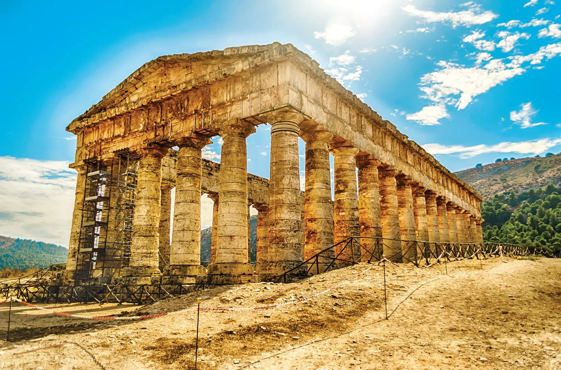 The Doric temple of Segesta standing on a dry hillside under blue sky