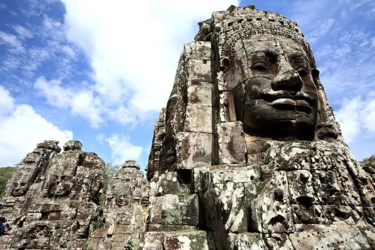 A great carved stone face on a tower of the Bayon against blue sky
