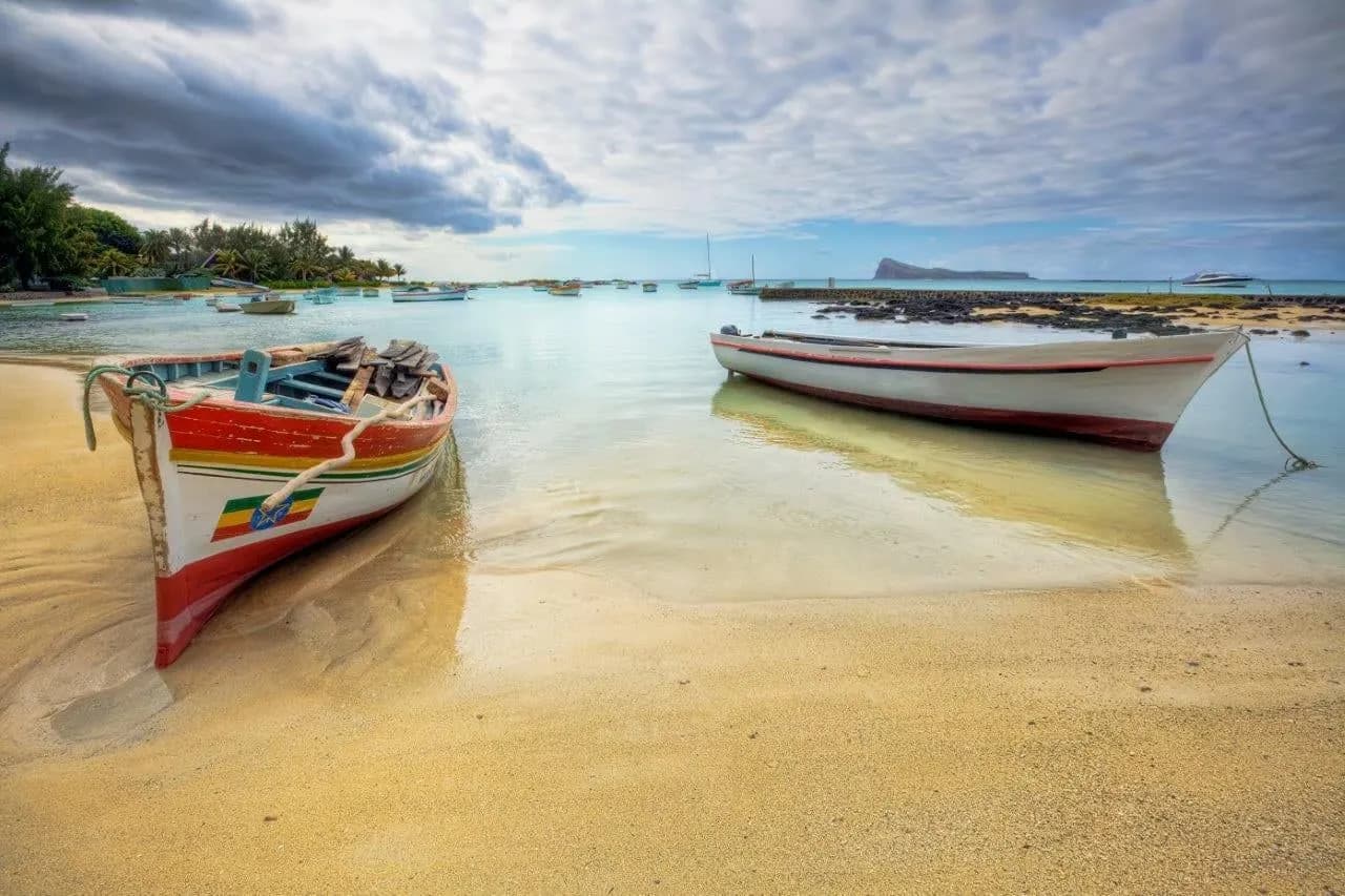 Painted wooden fishing boats resting in a calm, shallow lagoon