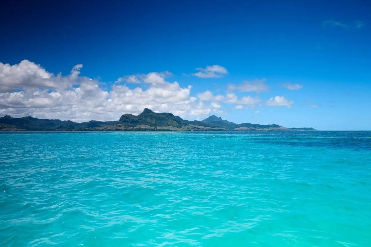 Turquoise water off the coast, with green mountains on the horizon