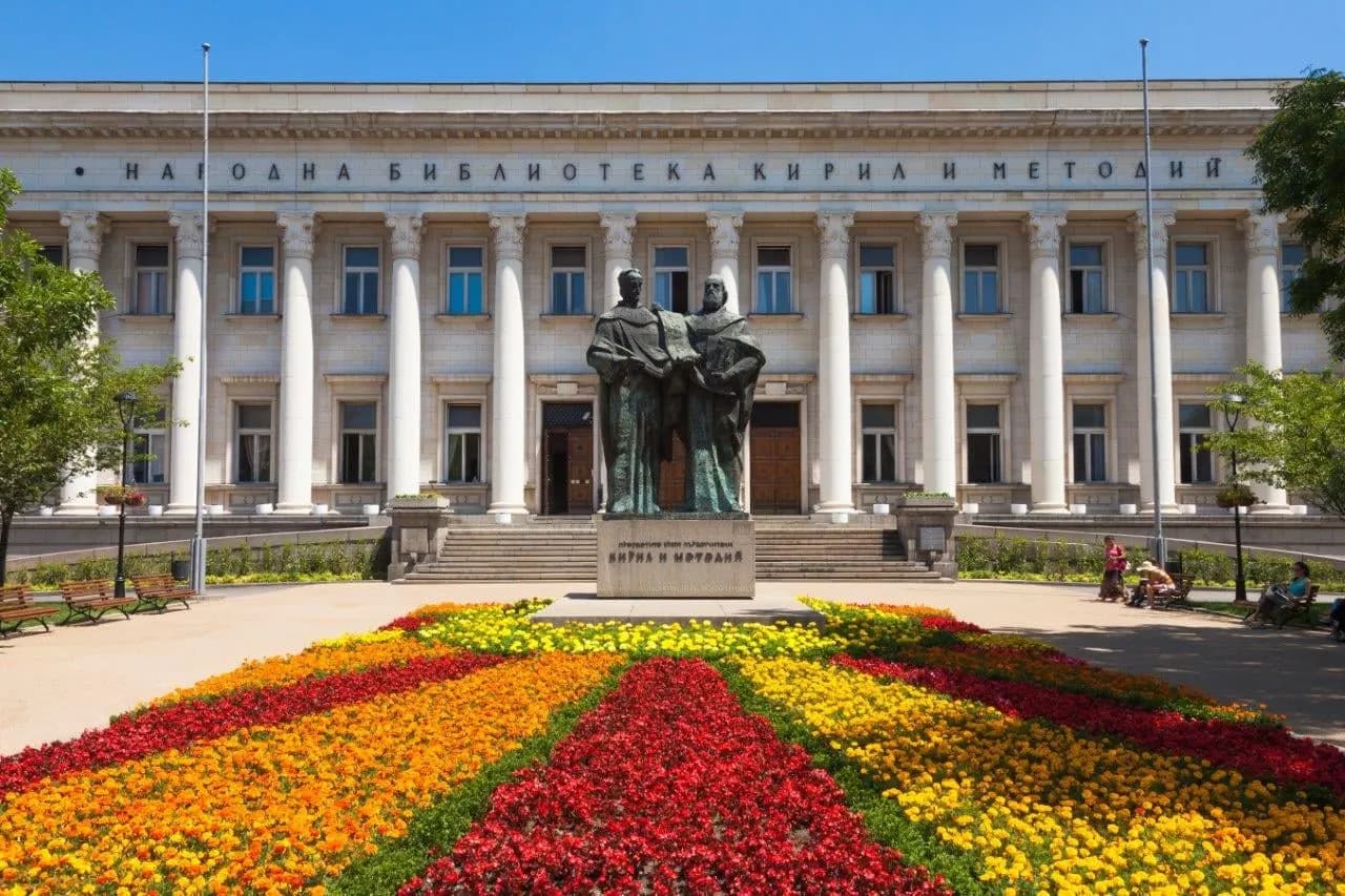The National Library in Sofia behind a statue and beds of red and yellow flowers