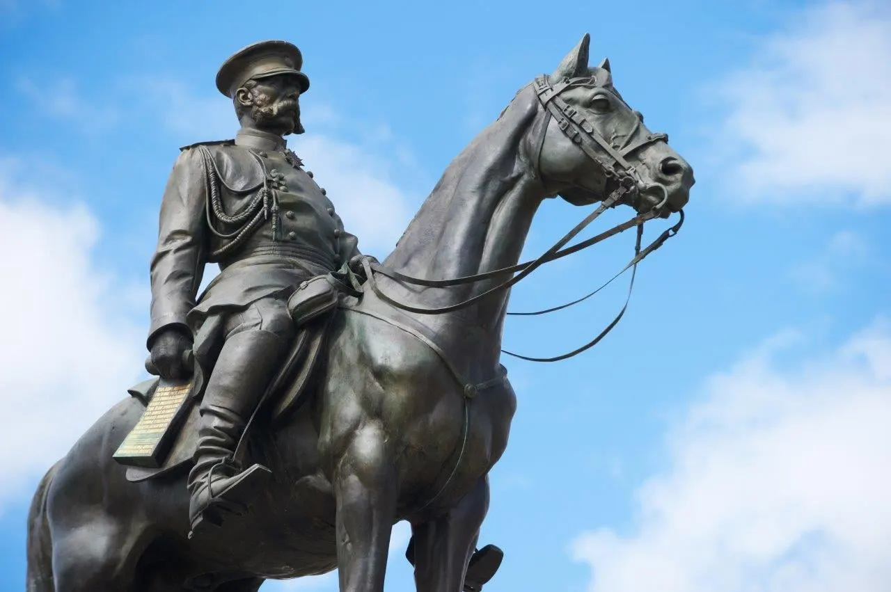 A bronze statue of a rider on horseback against a blue sky