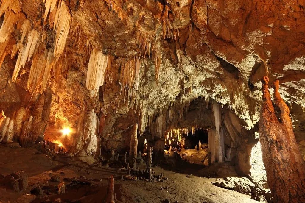 Lit stalactites and stalagmites inside a limestone cave