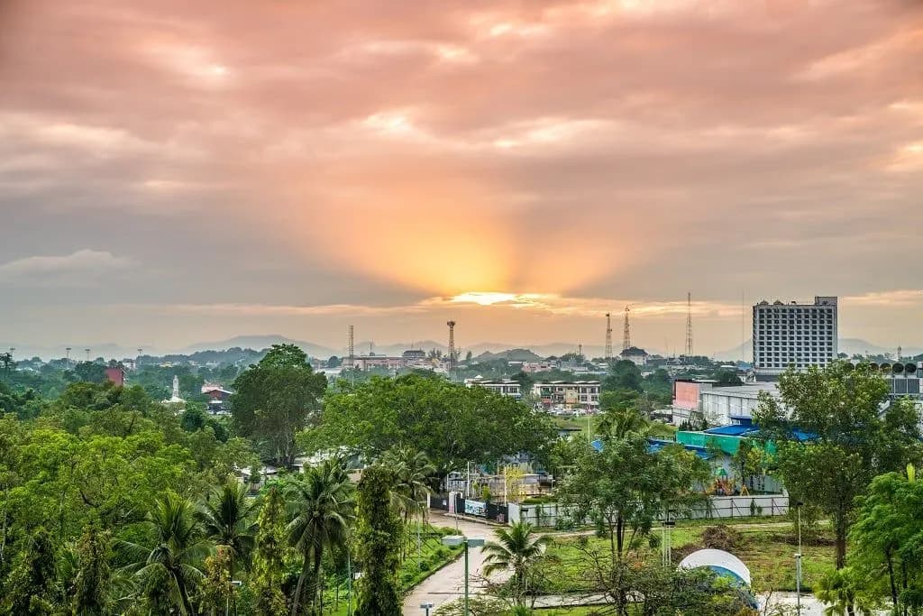 Sunset over the rooftops and trees of a southern Thai town