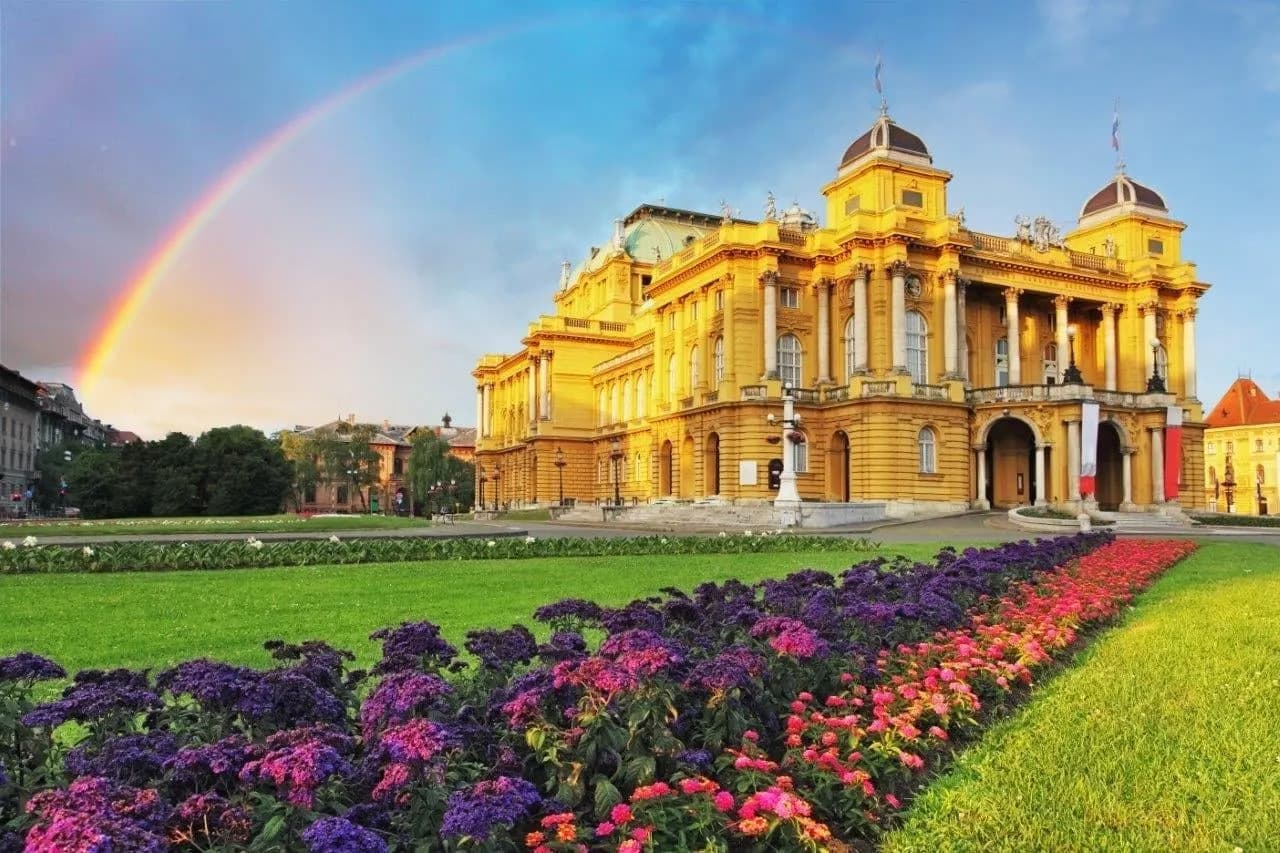 The yellow Croatian National Theatre in Zagreb behind flower beds