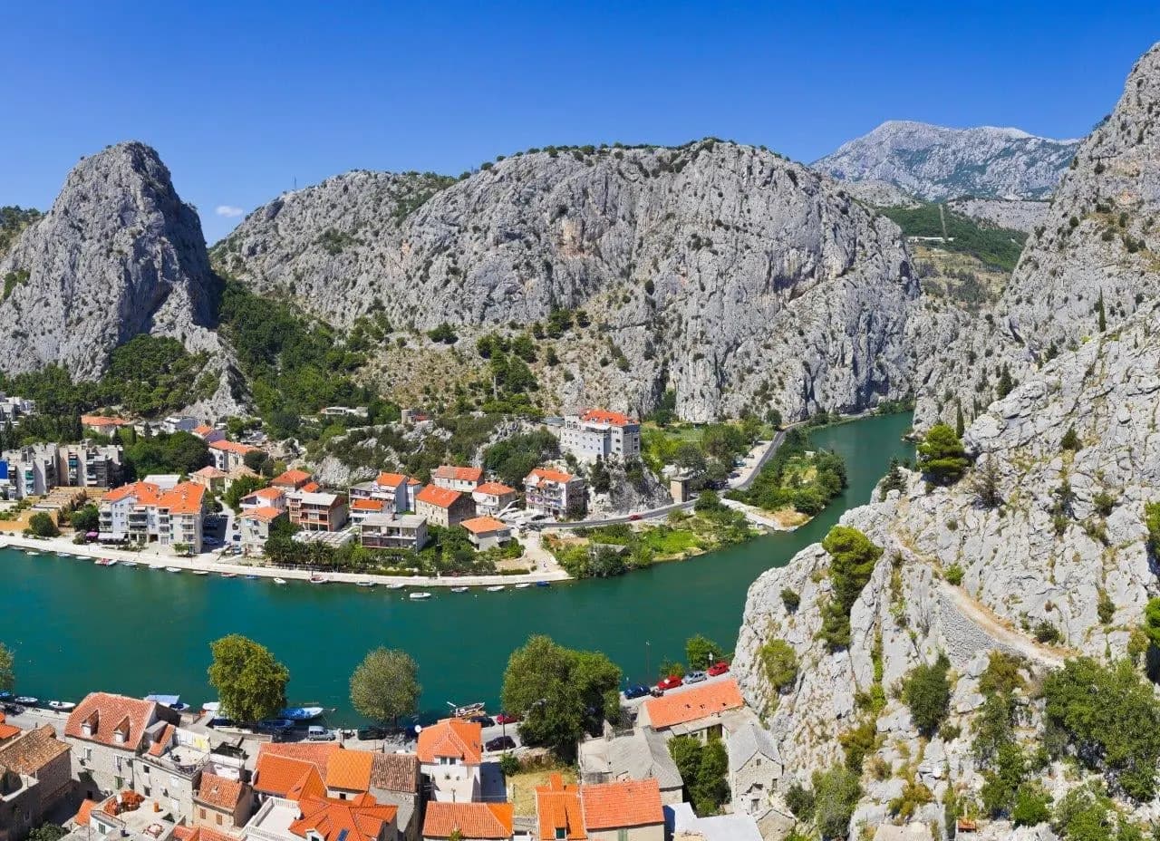 A red-roofed river town beneath steep limestone cliffs near Split