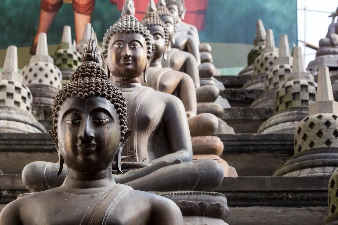 Rows of seated bronze Buddha statues at a temple