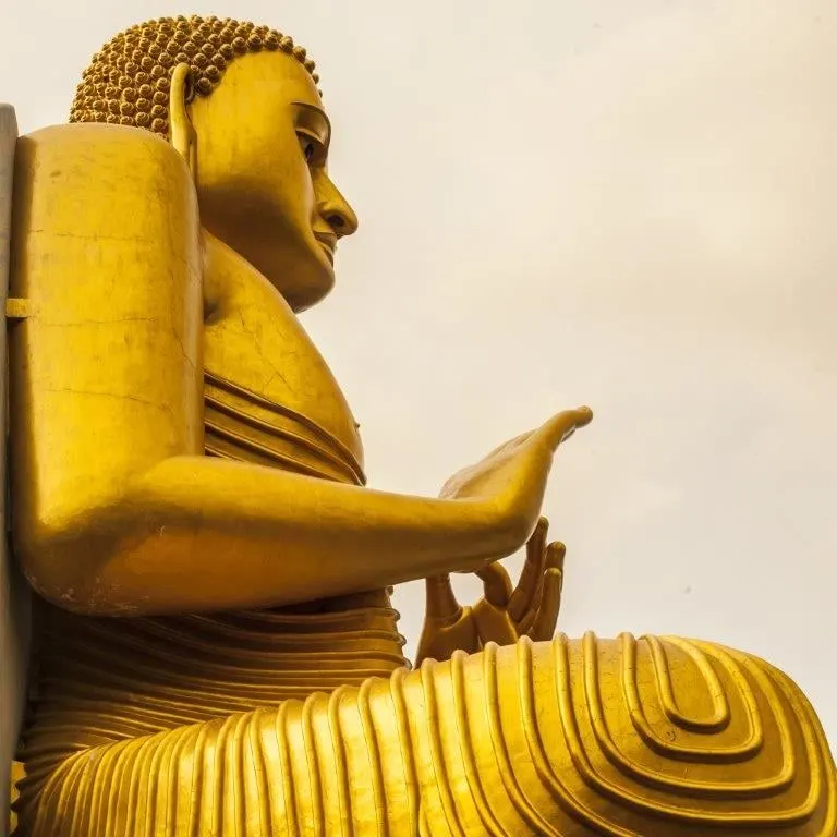 A giant golden seated Buddha statue against a pale sky