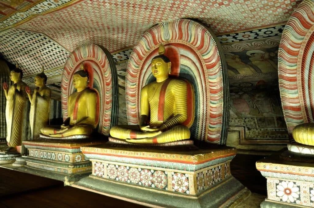 Painted seated Buddha statues inside a cave temple