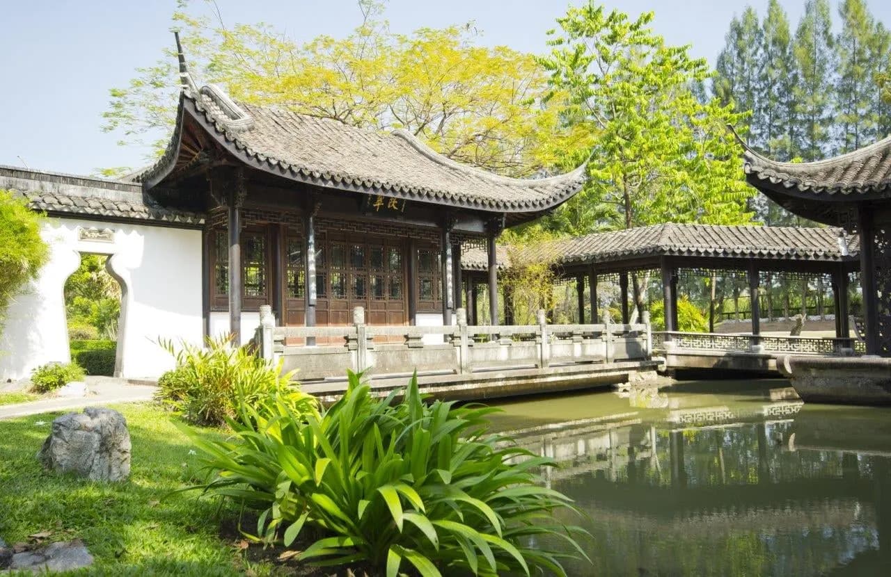 A classical Chinese garden pavilion and bridge reflected in still water