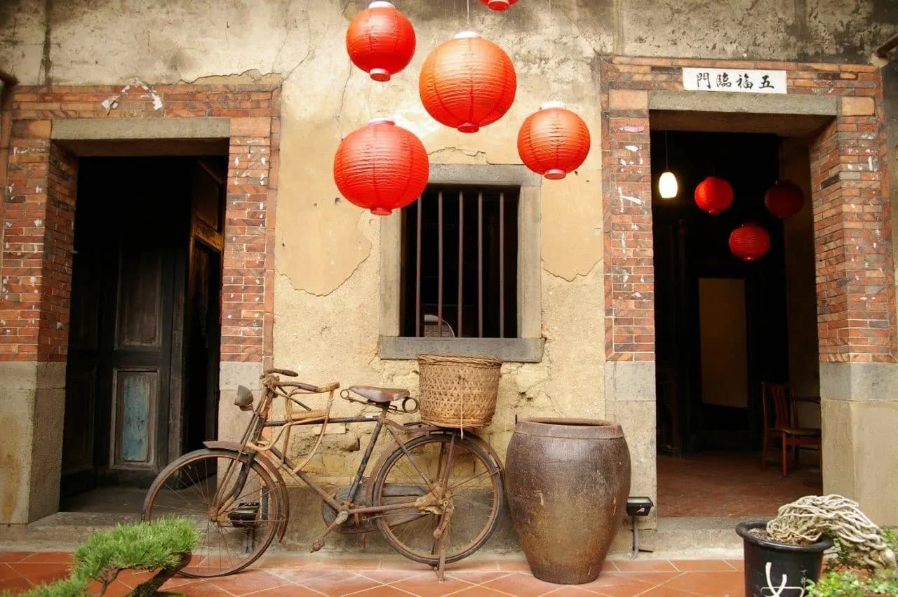 Red lanterns and an old bicycle outside a brick doorway