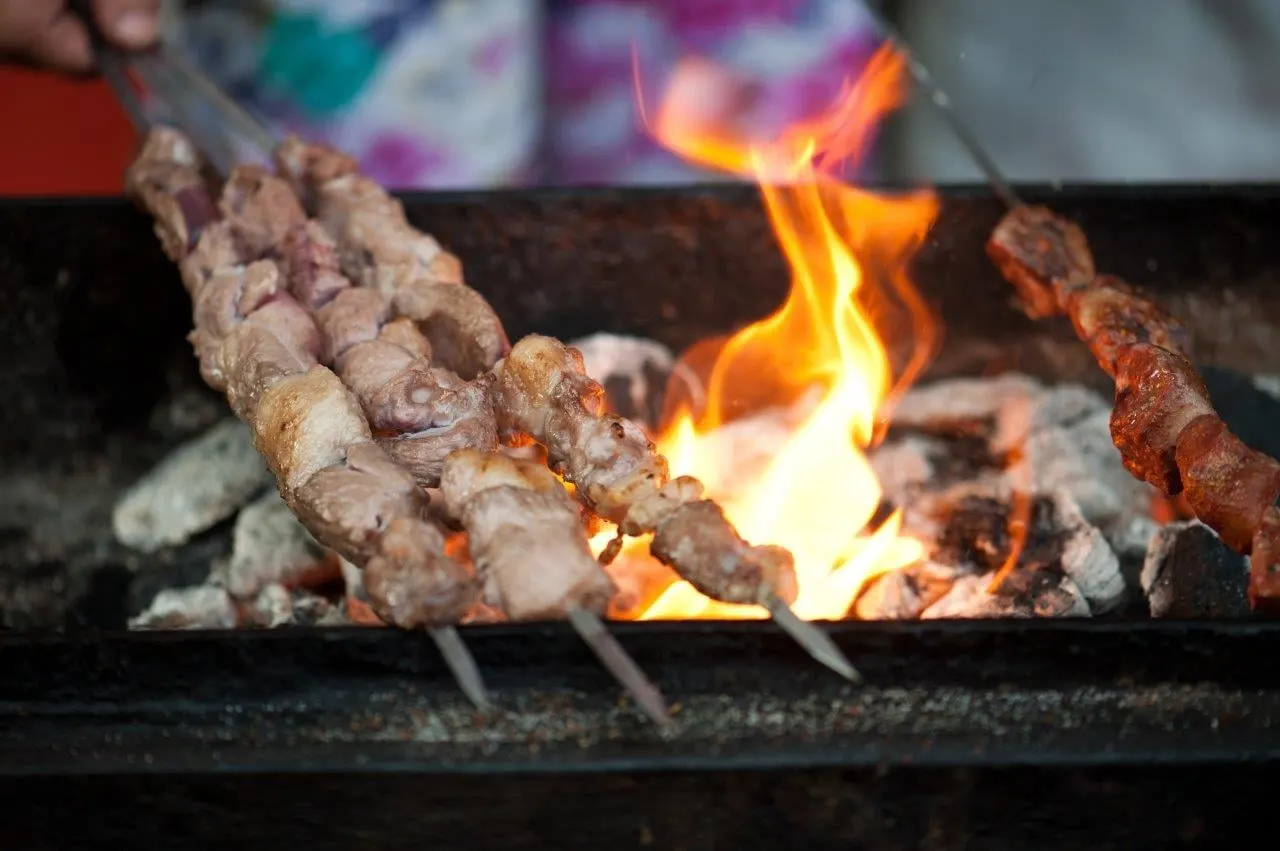 Meat skewers cooking over an open charcoal flame