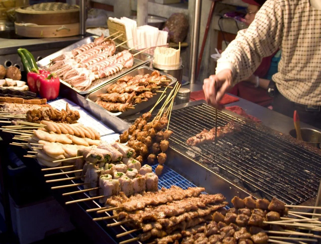 Skewers and snacks laid out on a street food grill