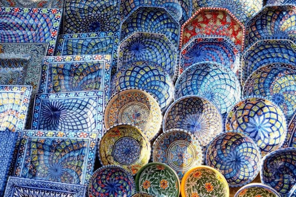 Hand-painted ceramic bowls and plates stacked for sale