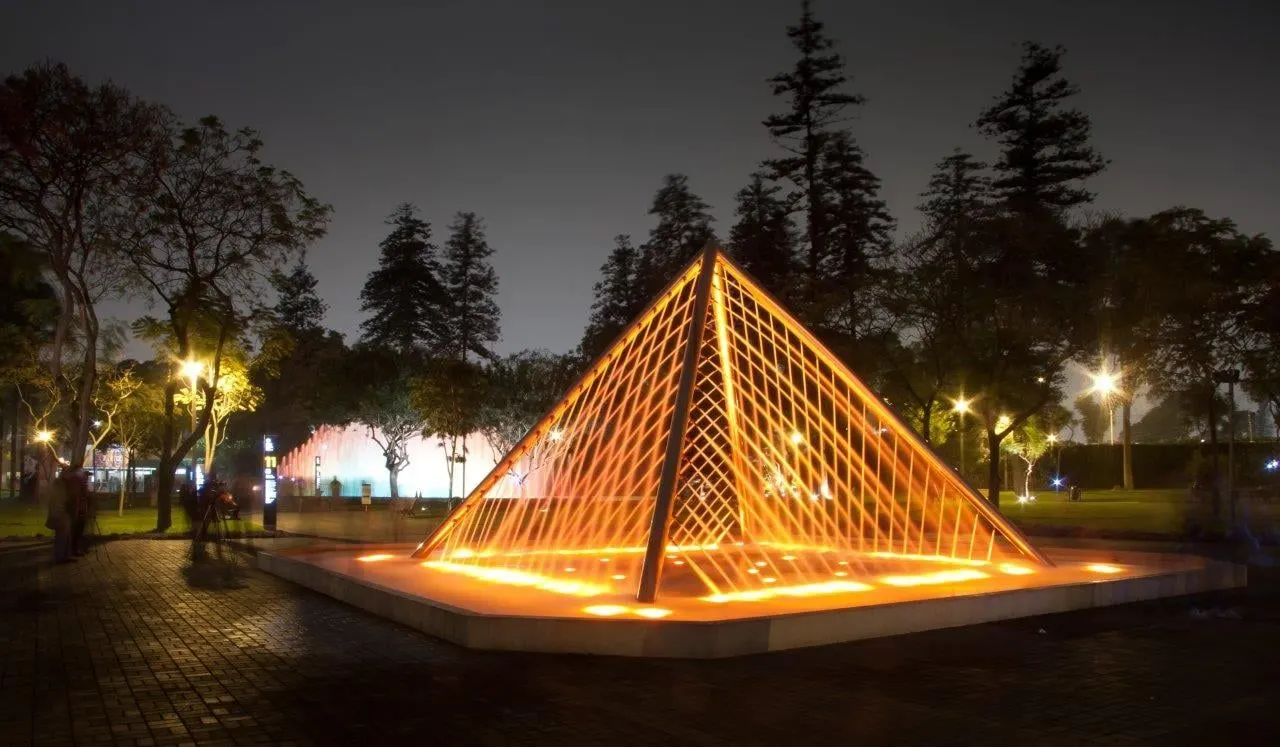 A lit pyramid-shaped fountain in a Lima park at night
