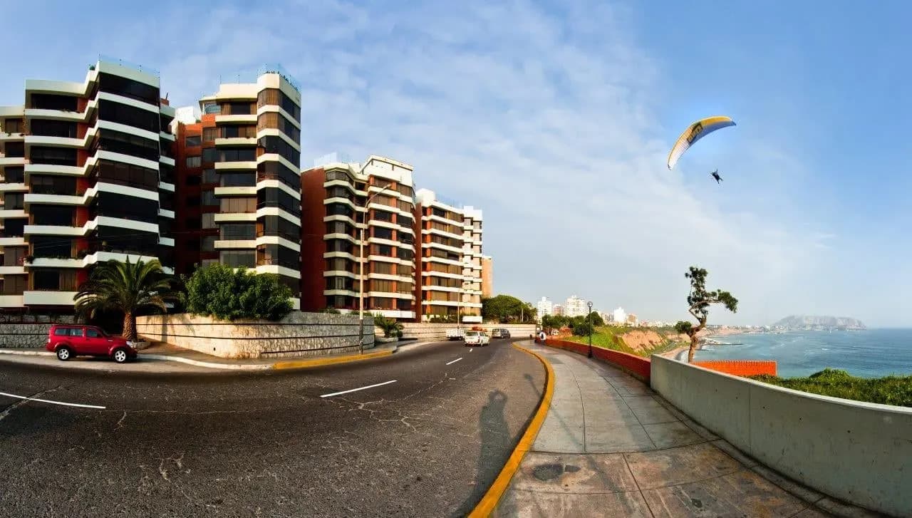 A paraglider above the Miraflores clifftop road and apartment towers