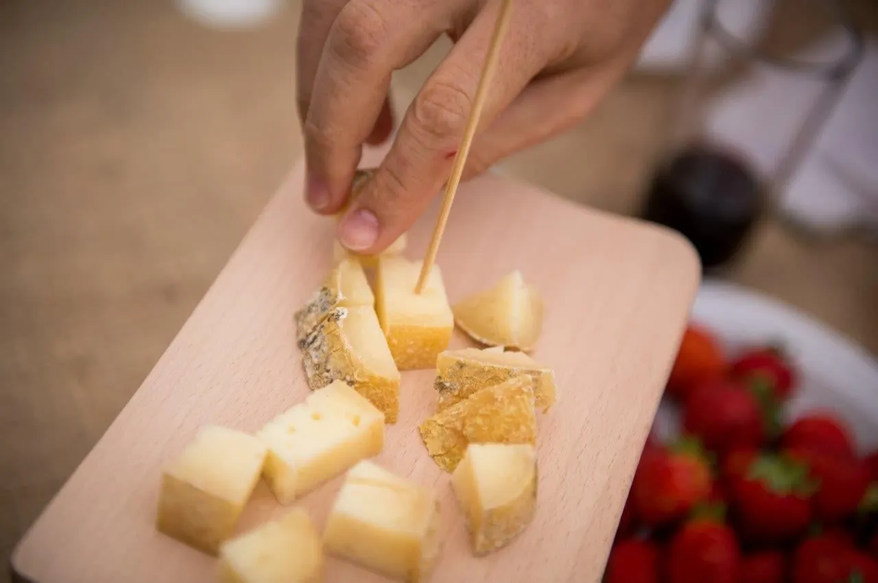 Cubes of local cheese on a wooden board, with strawberries alongside