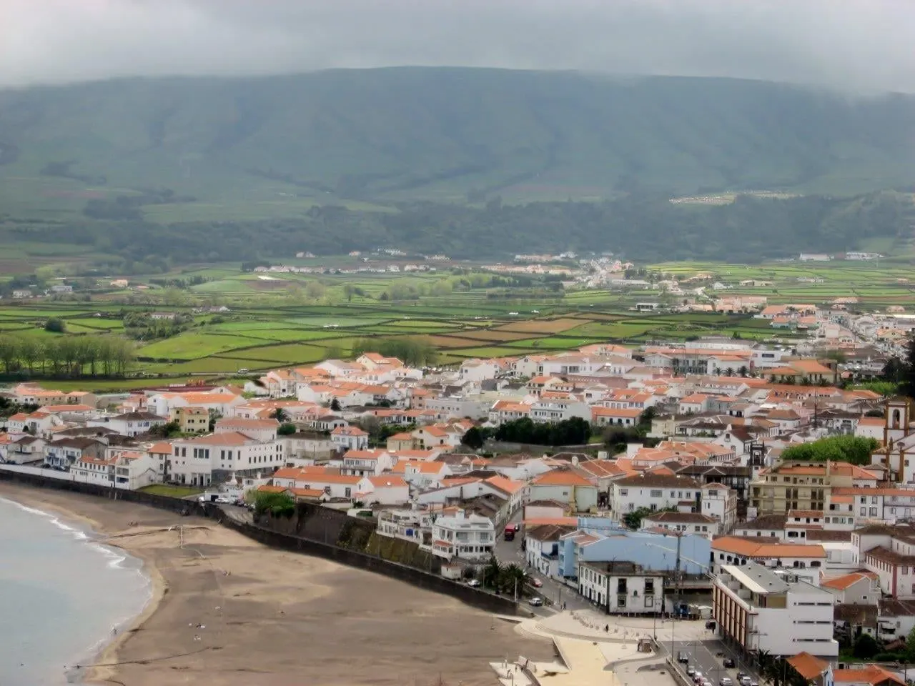The town and sandy bay of Praia da Vitória with green hills behind