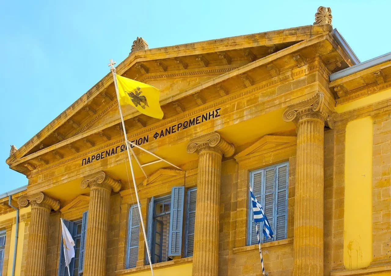 A yellow neoclassical facade with columns and flags