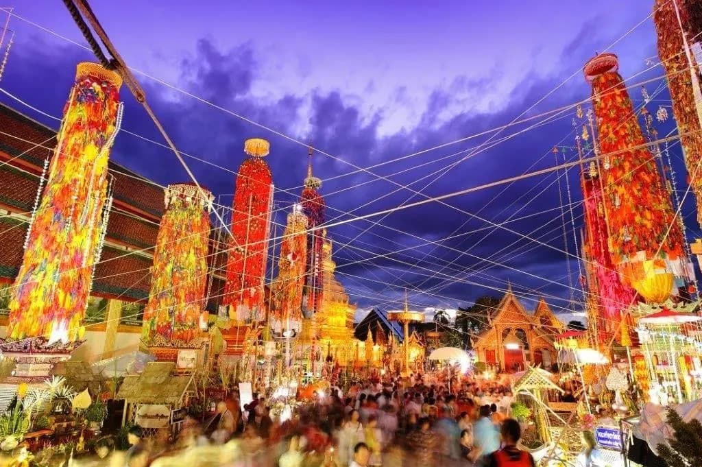 Tall towers of paper lanterns lit up at a northern Thai temple fair at dusk