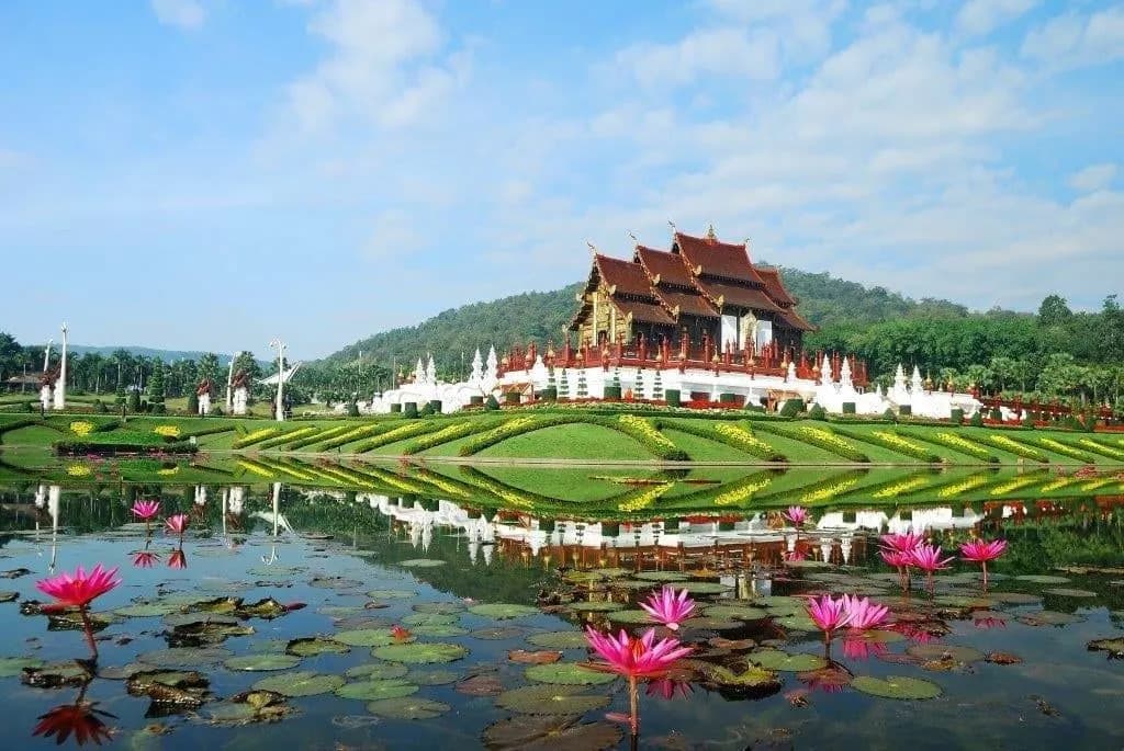 A Lanna-style royal pavilion behind a pond of pink lotus flowers near Chiang Mai