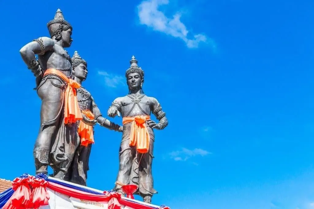 The bronze statues of the Three Kings Monument in Chiang Mai against a blue sky