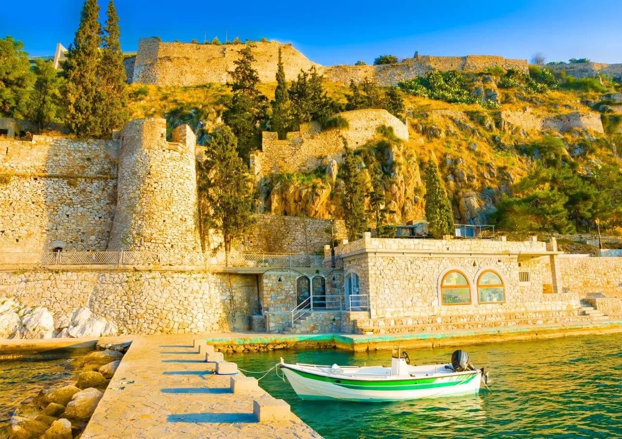 Old stone walls and a small boat by the harbour in Nafplio