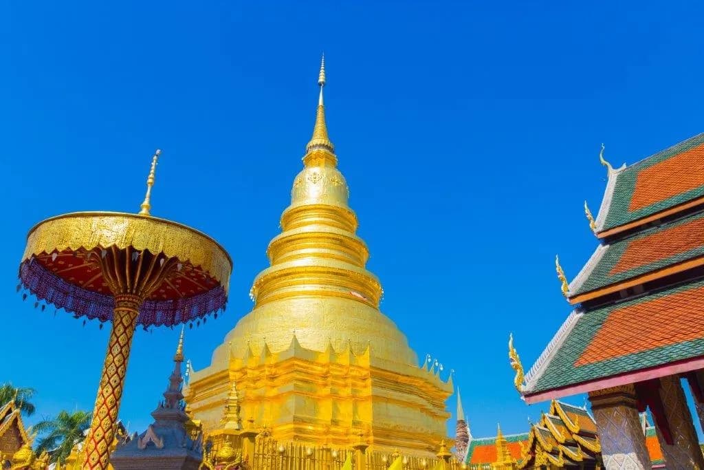 A golden Buddha in a red and gold temple hall in northern Thailand