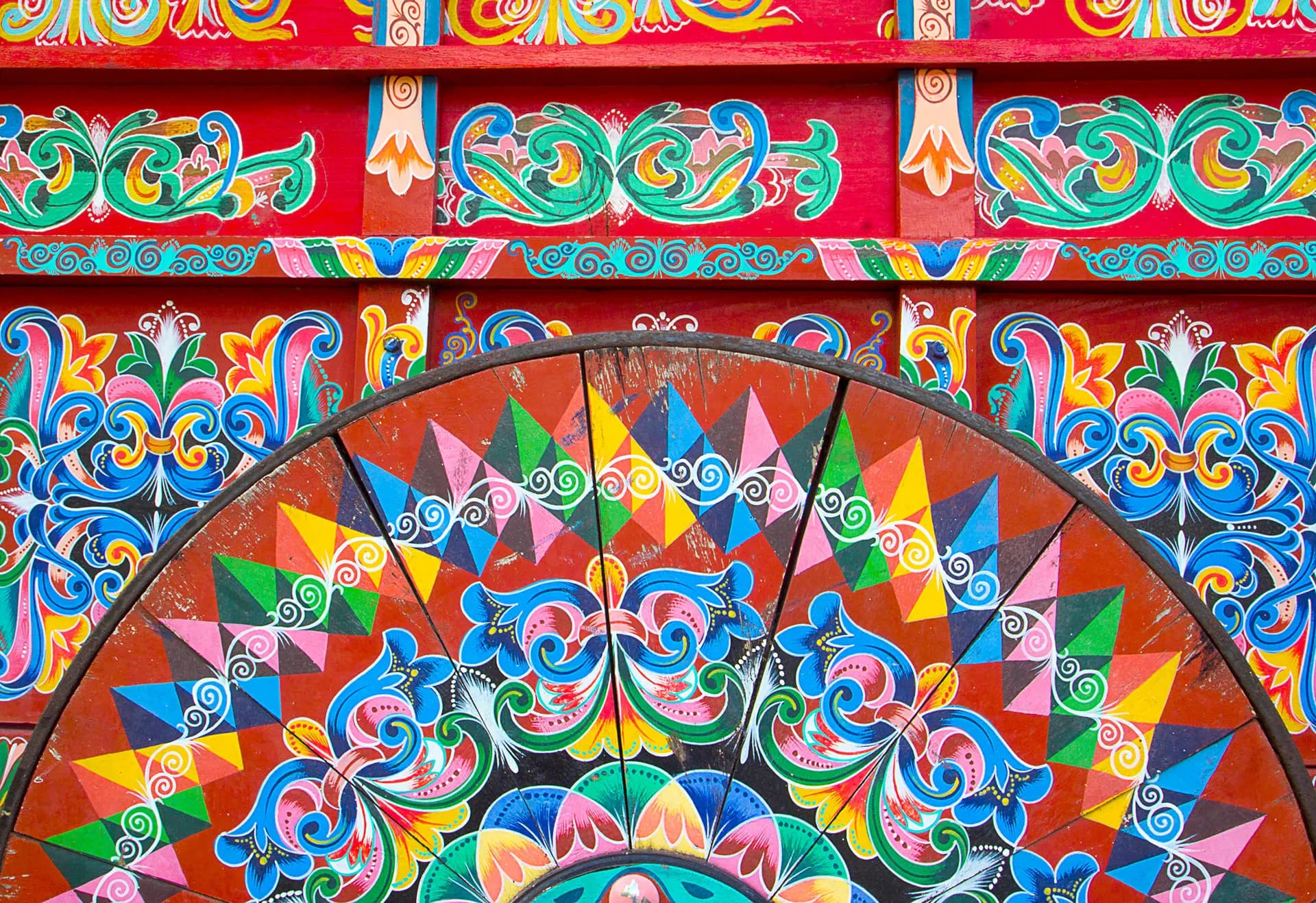 Close view of a brightly painted ox cart wheel in red, blue and gold