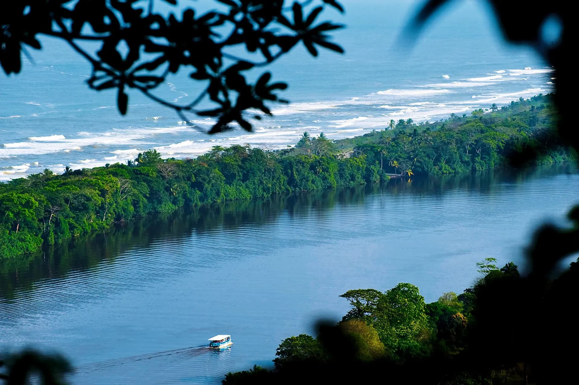 A boat on a lagoon between rainforest and the Caribbean surf at Tortuguero